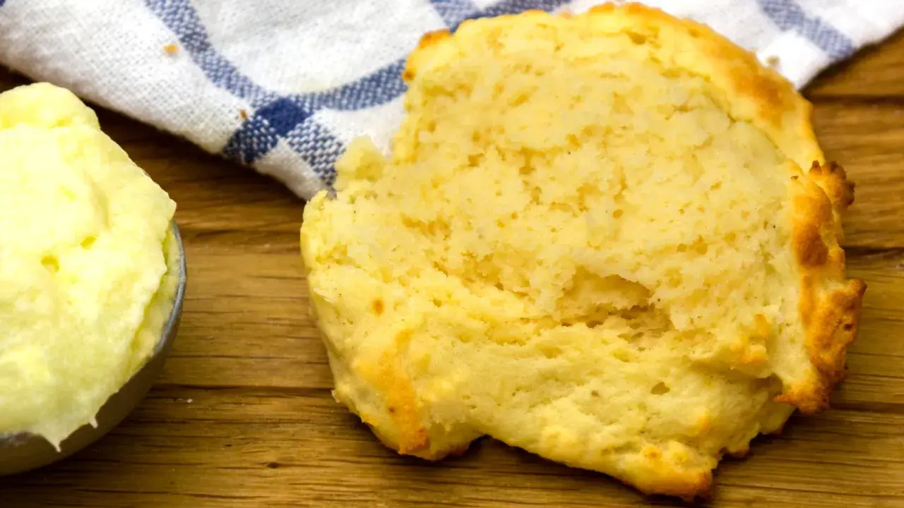 En fluffig scone bredvid en skål med mjukt, flytande margarin, redo att avnjutas.
