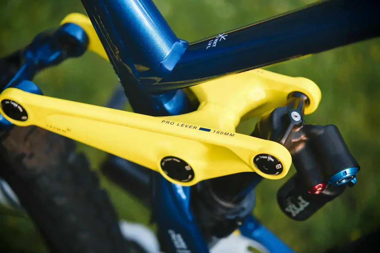 Żółte ramię korby z napisem "PRO LEVER 180MM" na tle niebieskiej ramy roweru.