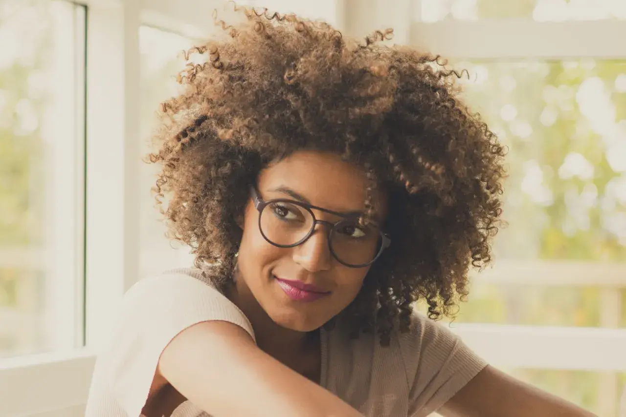 Frau mit vollem Haar und modischem Brillengestell, das ihren brillen style unterstreicht.