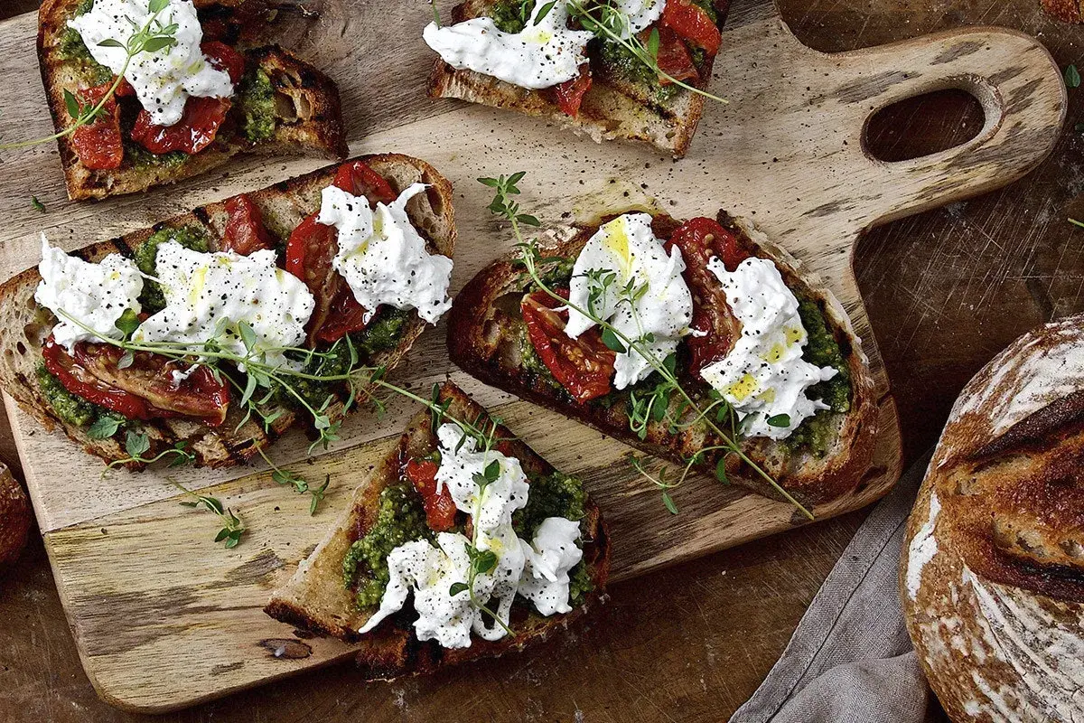Grillade bruschetta med krämig ost, soltorkade tomater och pesto. En härlig ostupplevelse!