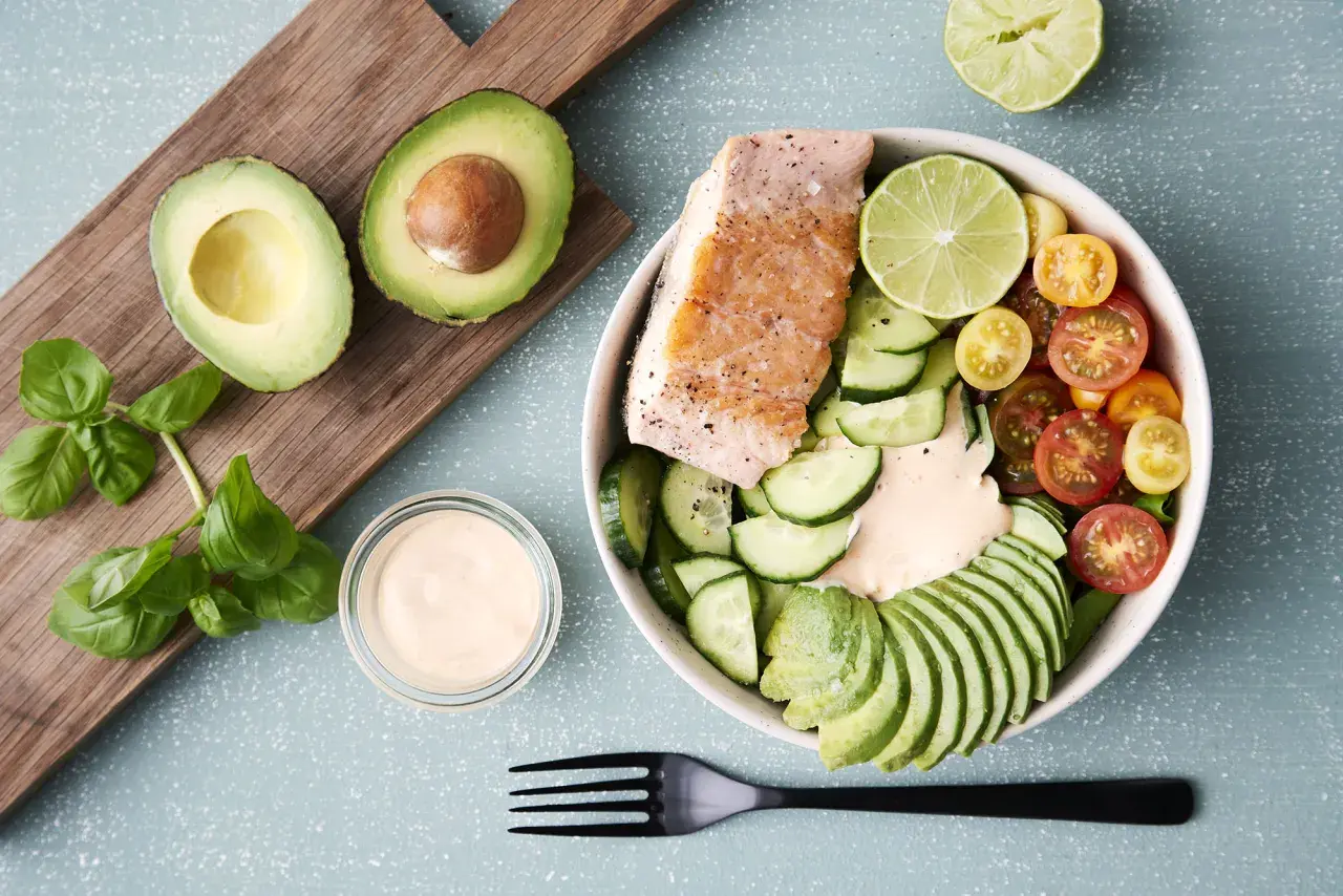 En härlig keto recept-bowl med lax, avokado, gurka, tomater och en krämig dressing. Perfekt för en hälsosam lunch.