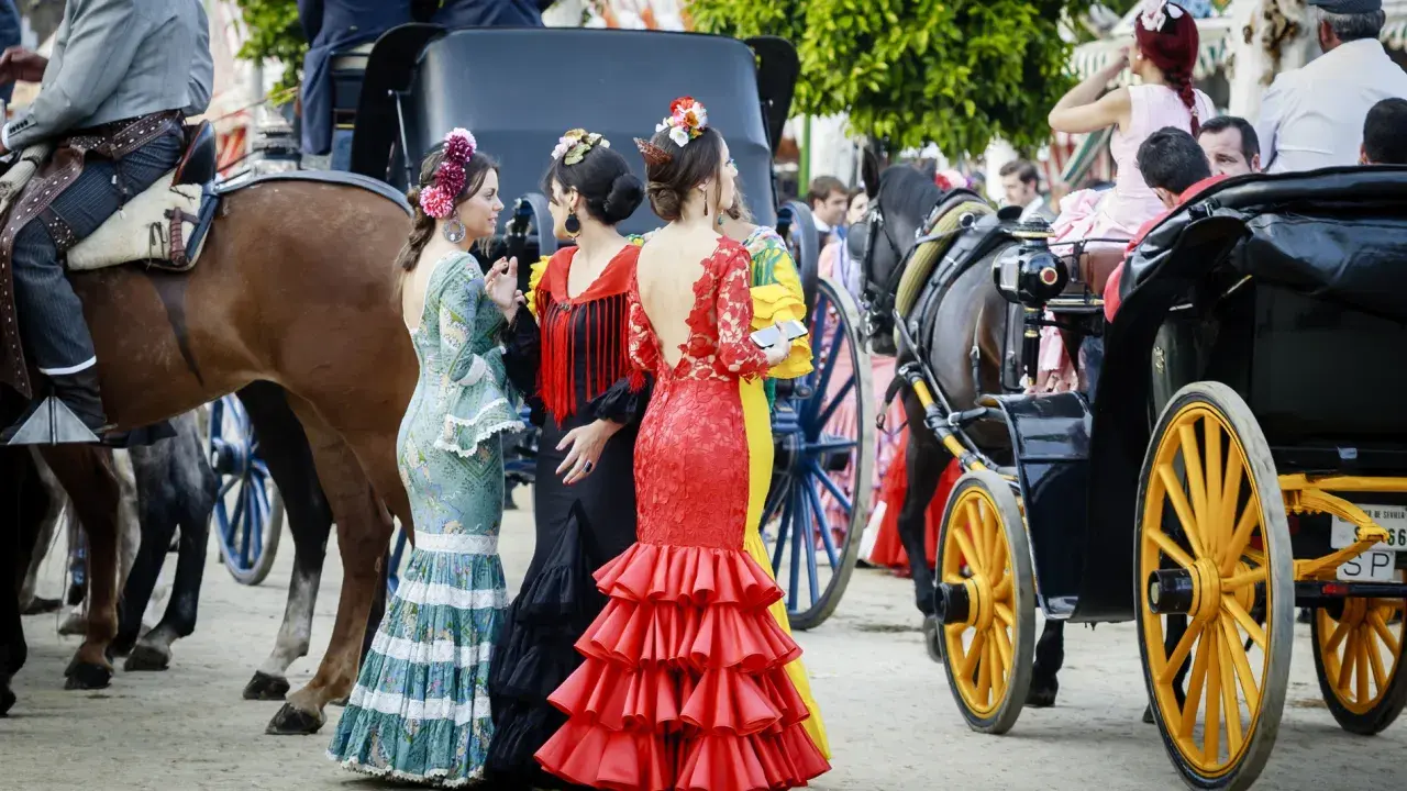 Mujeres con trajes de flamenca y caballos, evocando de donde proviene el flamenco.