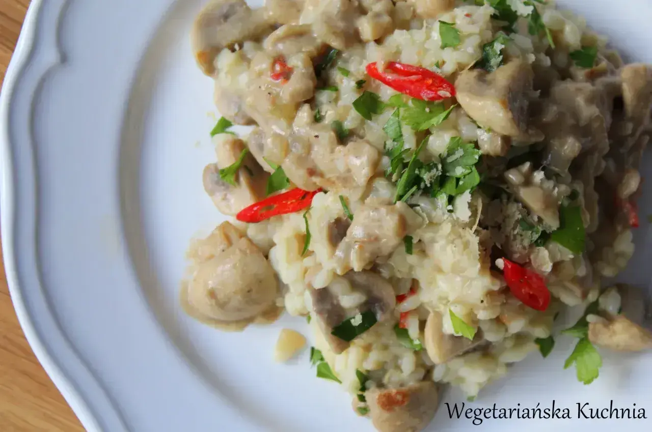 Kremowe risotto z pieczarkami, ozdobione natką pietruszki i ostrą papryczką. Idealne danie dla miłośników grzybów.