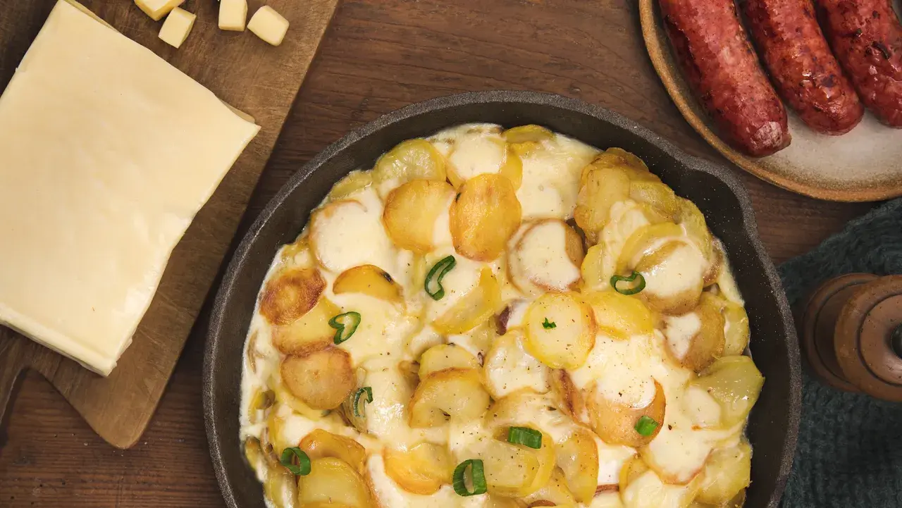 Plat gratiné de pommes de terre et fromage fondant, parfait pour une recette diots de Savoie. Accompagné de saucisses savoureuses.
