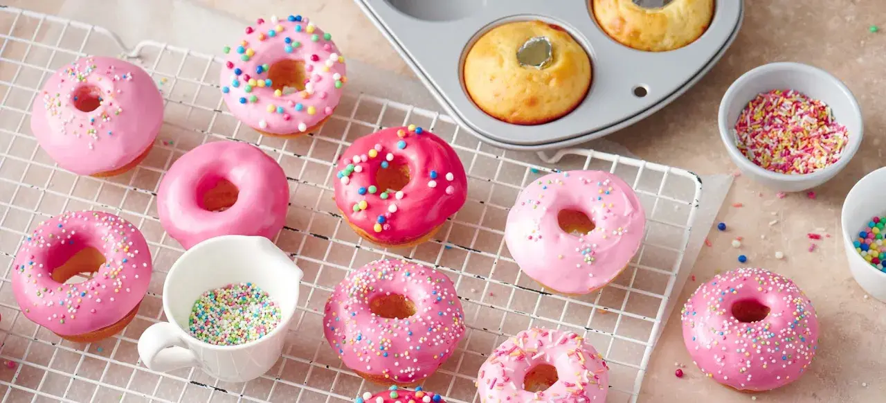 Deliciosos donuts rosados y brillantes, listos para decorar. Una tentadora receta de donuts para disfrutar.