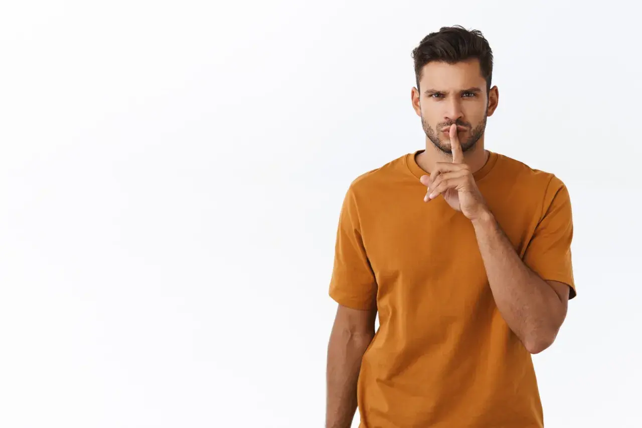 Uomo con dito sulle labbra, sguardo intenso. Un chiaro messaggio: quando un uomo ti dice lasciami in pace, è meglio ascoltare.