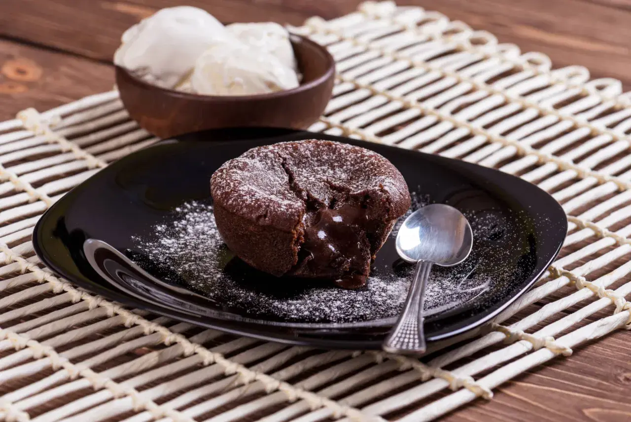 Un délicieux moelleux au chocolat, cœur coulant, saupoudré de sucre glace, servi avec de la glace à la vanille. Une recette gourmande à tester !