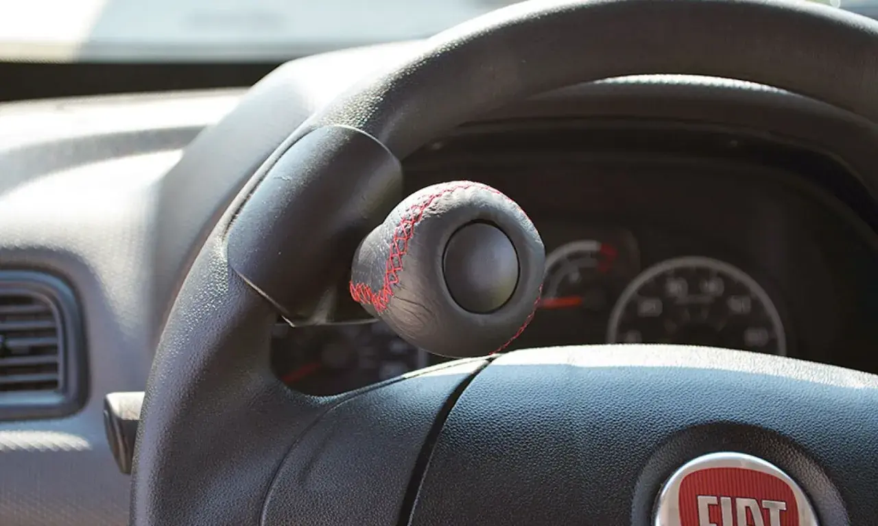 Pomello volante in pelle nera con cuciture rosse, un accessorio che rispetta la normativa per una guida sicura e personalizzata.