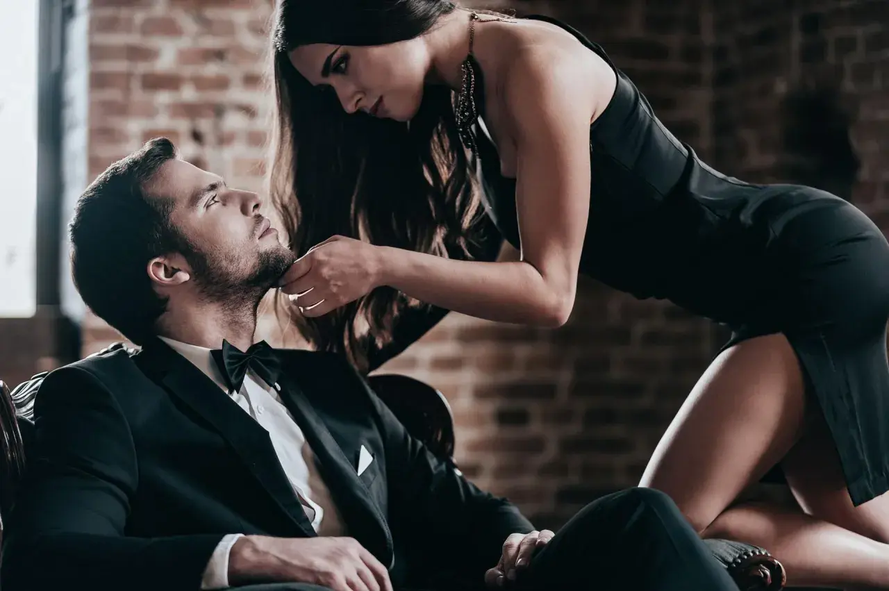Elegancki mężczyzna w garniturze i kobieta w czarnej sukience. Sekret jak być atrakcyjnym tkwi w pewności siebie i spojrzeniu.