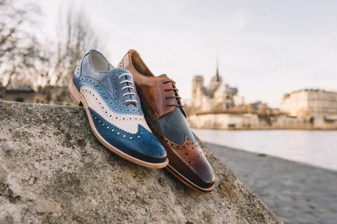 Eleganckie męskie buty derby, jeden w odcieniach niebieskiego i białego, drugi brązowy. Idealne na spacer po Paryżu.