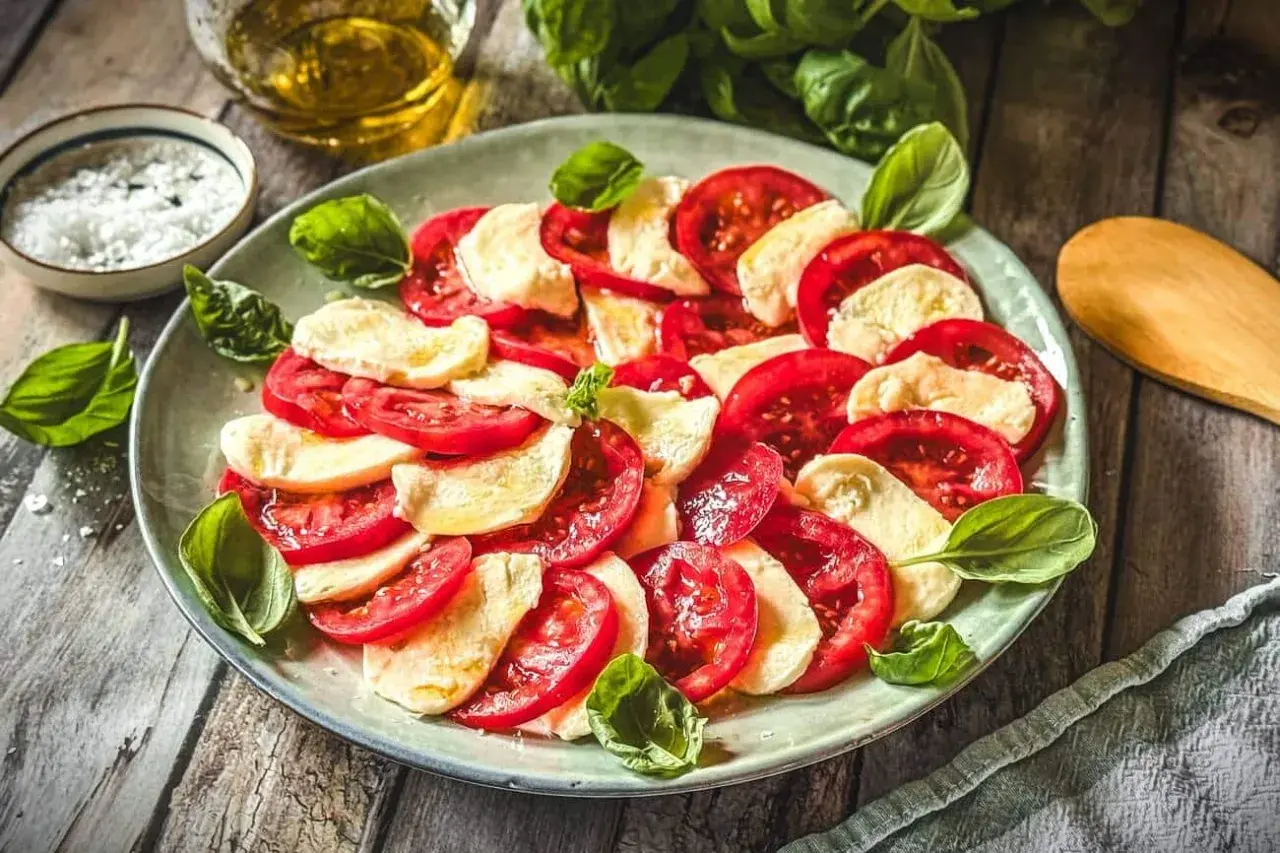 Frische Tomaten und Mozzarella, arrangiert als klassische Caprese. Ein einfaches, aber köstliches Gericht, das die Aromen Italiens feiert.