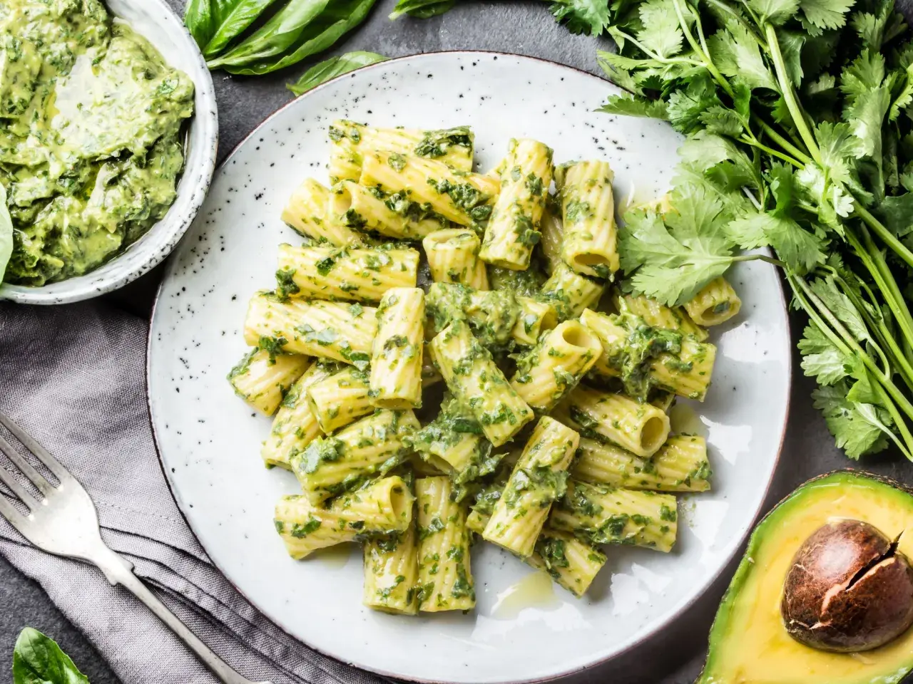 Rigatoni-Nudeln mit cremigem Avocado-Pesto, garniert mit frischem Koriander und Basilikum.
