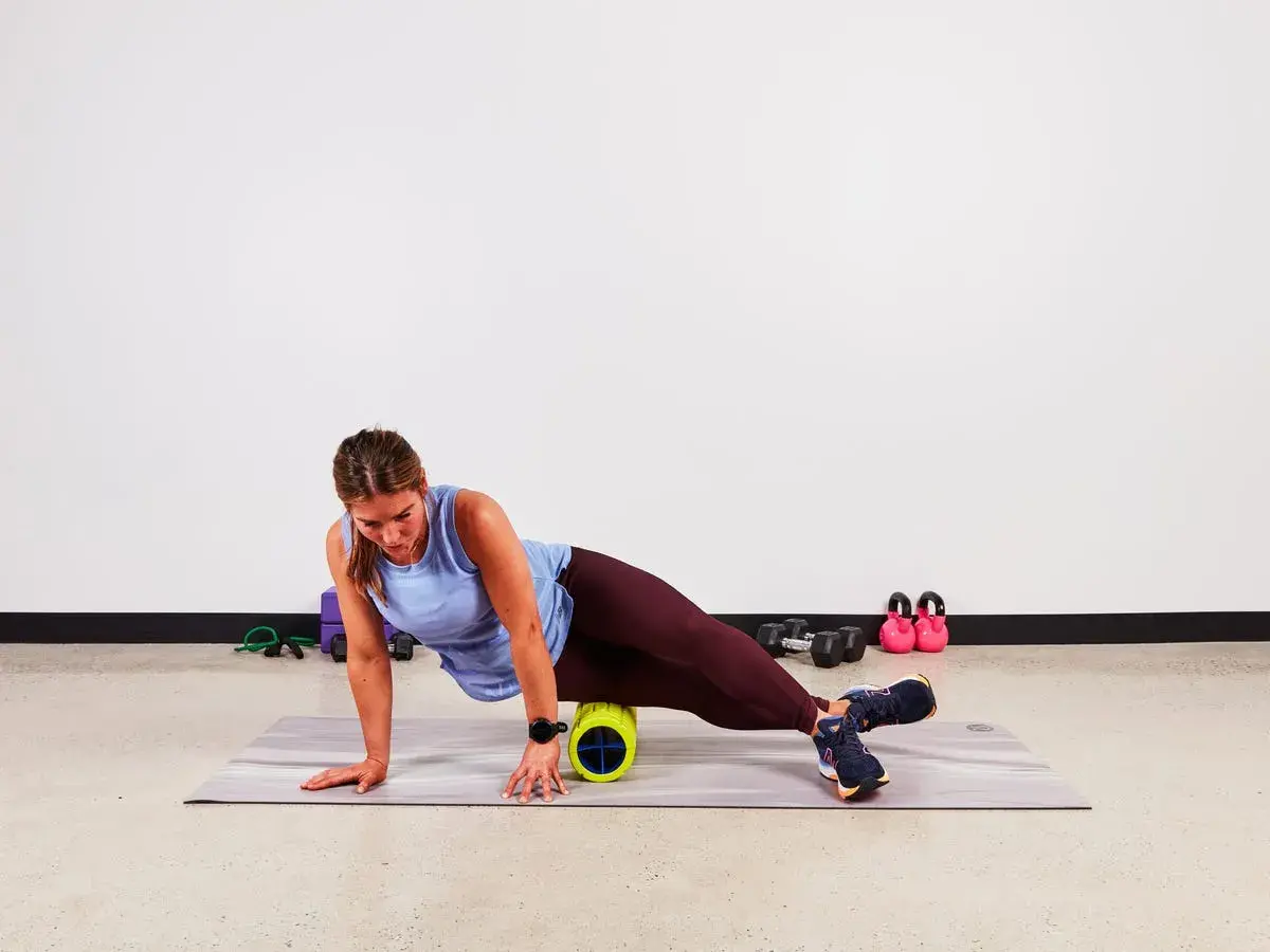 Donna usa un foam roller per alleviare la bandelletta ileotibiale. Soluzioni per il recupero muscolare.