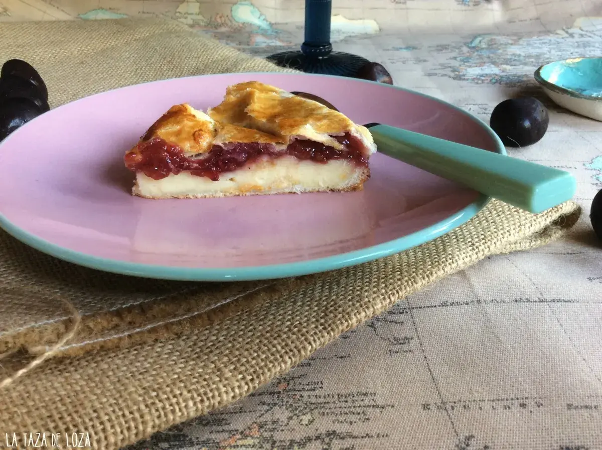 Porción de pastel vasco con relleno de crema y frutos rojos, servida en plato rosa.
