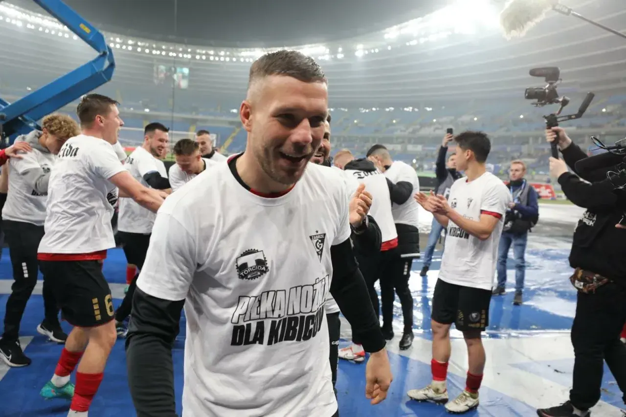 Piłkarze w białych koszulkach z napisem "Piłka nożna dla kibiców" świętują. To obraz z historii tabeli wszechczasów ekstraklasy.