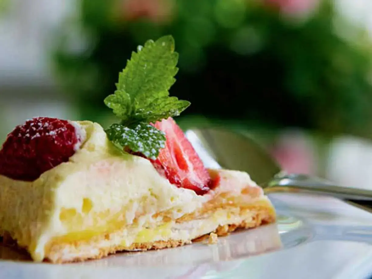En bit pavlova med lemoncurd, toppad med färska jordgubbar och mynta. En härlig sommardessert.