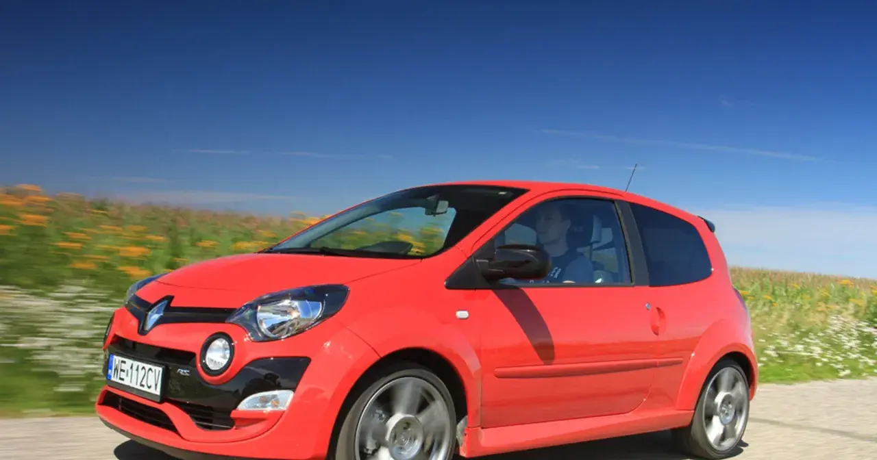 Czerwone Twingo RS pędzi przez kwitnące pola pod błękitnym niebem.