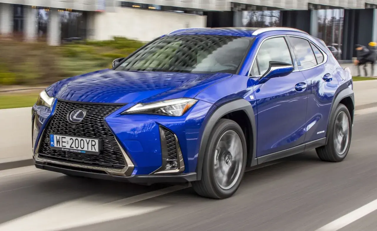 Błękitny Lexus UX 200 w ruchu miejskim, z widocznym grillem i reflektorami.