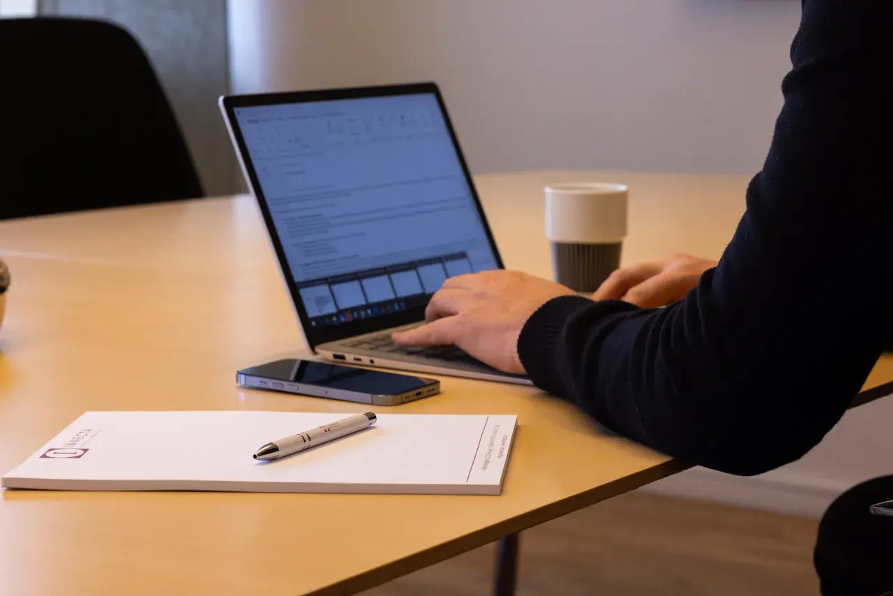 Person arbetar vid laptop, med mobil och anteckningsblock på bordet. Kanske planerar att låna ut pengar till aktiebolag.