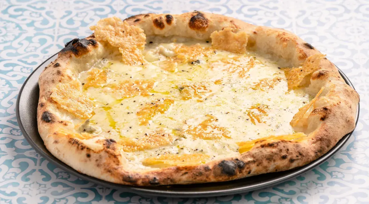 Eine köstliche Pizza Formaggi mit geschmolzenem Käse und knusprigem Rand, serviert auf einem Teller mit blau-weißem Muster.