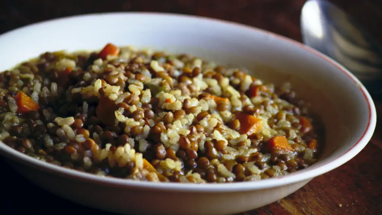 Un plato humeante de lentejas con arroz y trozos de zanahoria, listo para disfrutar.