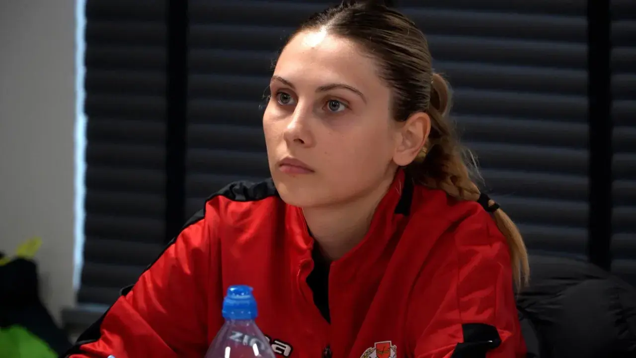 Młoda kobieta w czerwonej bluzie, przyszły trener UEFA A, słucha uważnie.