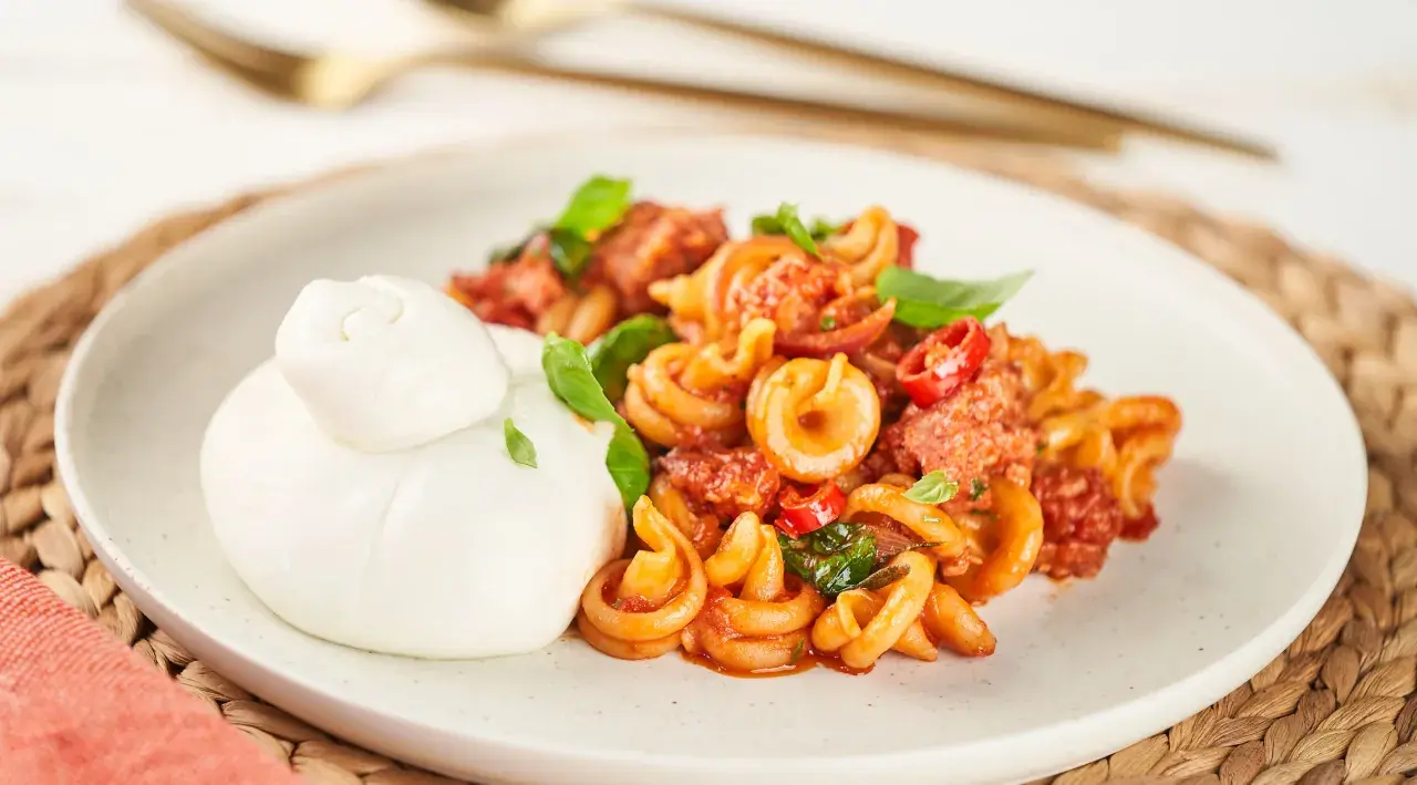 Pasta mit Salsiccia-Sauce und Burrata auf einem Teller.