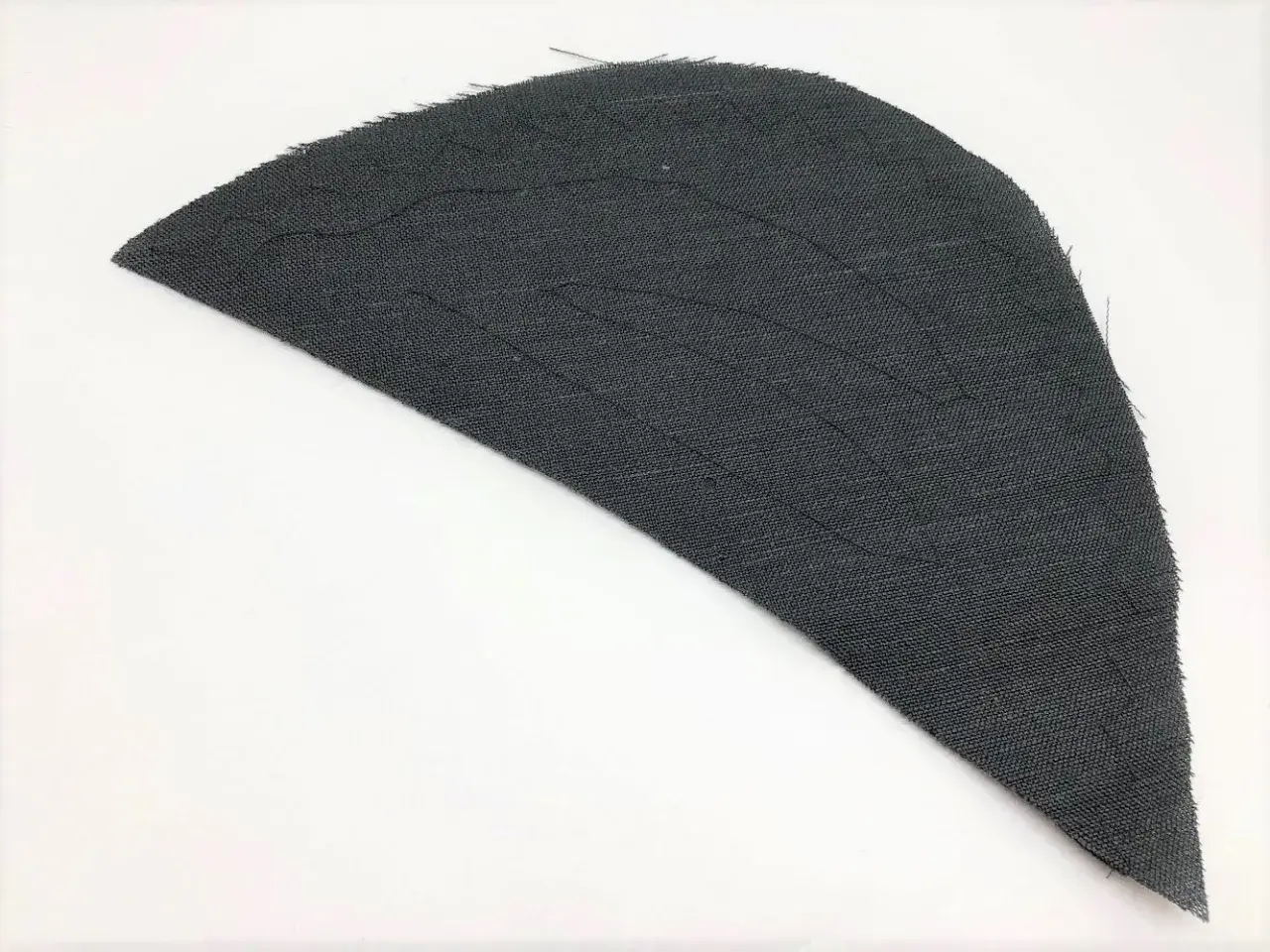 A dark gray fabric piece, shaped like a wing, shows stitching lines that form a shoulder pad pattern.