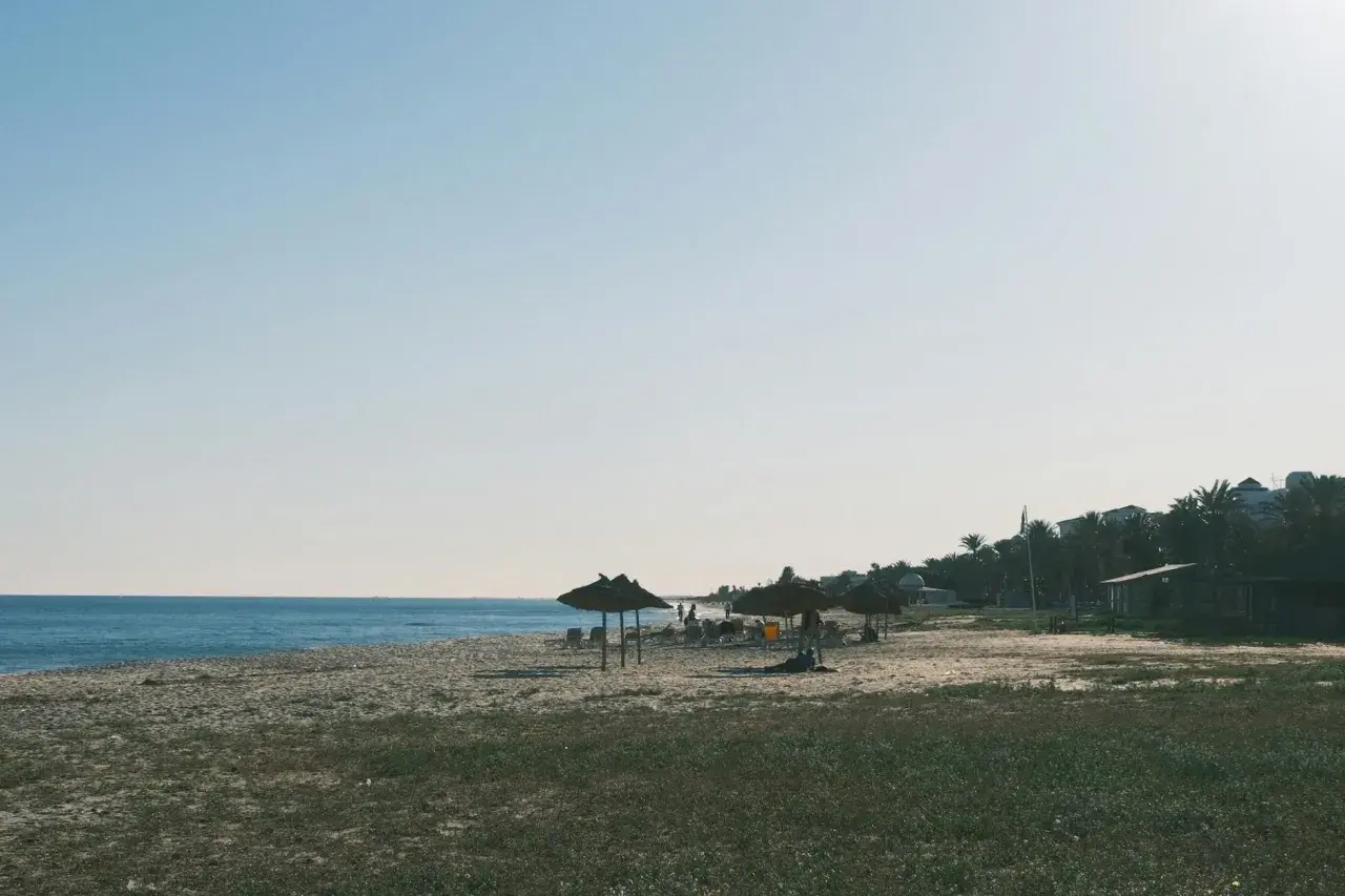 Spokojne tunezyjskie plaże z palmami i słomianymi parasolami. Idealne miejsce na relaks.