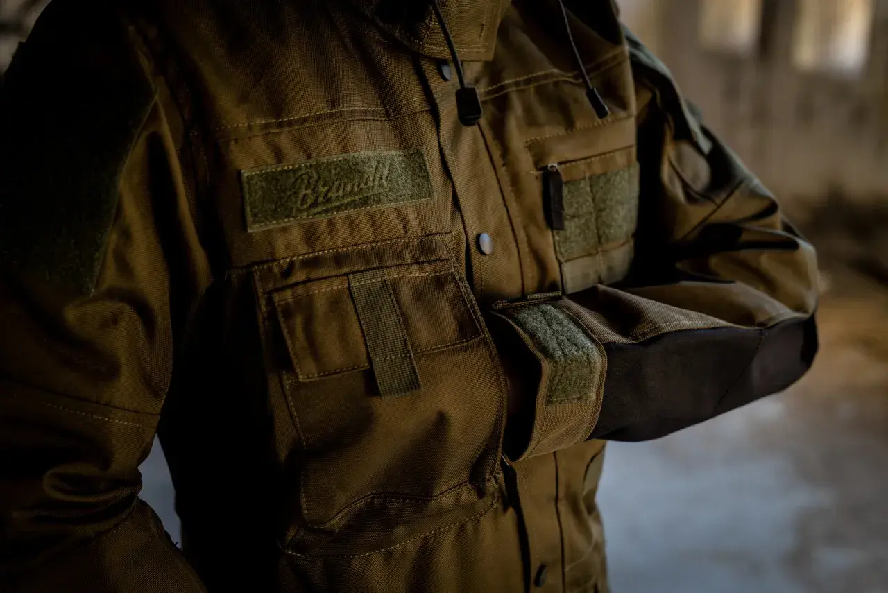 Kurtka z wytrzymałego materiału cordura, z licznymi kieszeniami i naszywkami. Idealna na wyprawy.