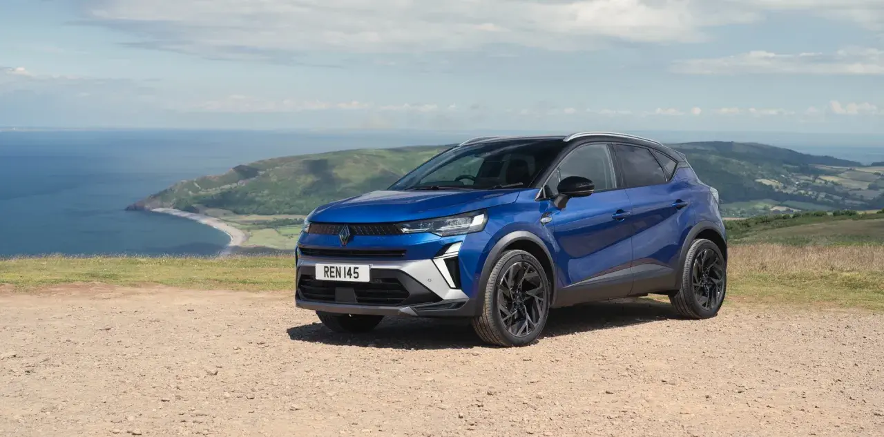 Niebieski Renault Captur na tle malowniczego wybrzeża. Idealny wybór na wakacyjne podróże, dostępny w atrakcyjnym **Renault w leasingu**.