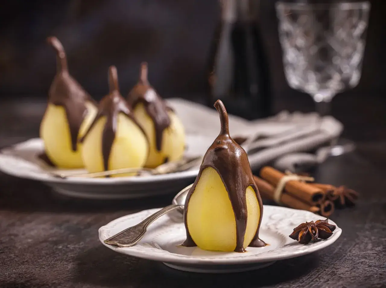 Poires pochées nappées de chocolat, un délice de poire belle Hélène. Cannelle et anis étoilé en arrière-plan.