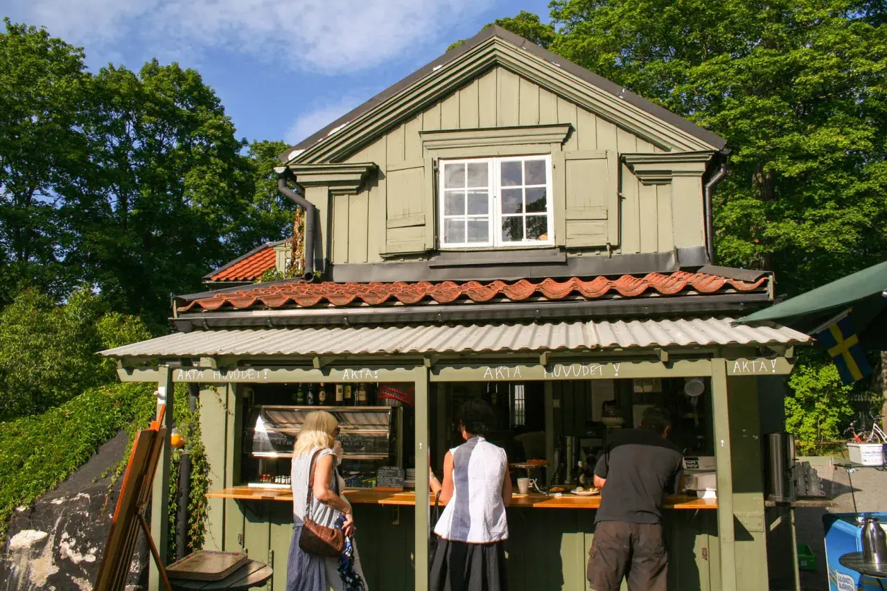 Vid Waldemarsudde café beställer folk fika i solen.