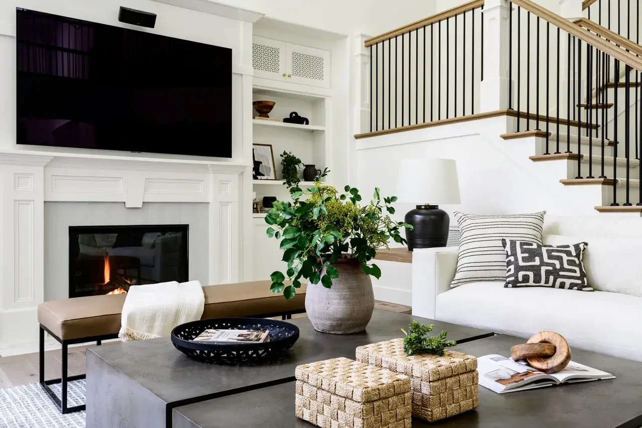 Stylish coffee table decor ideas: woven boxes, a black tray with a magazine, and a large vase with greenery.