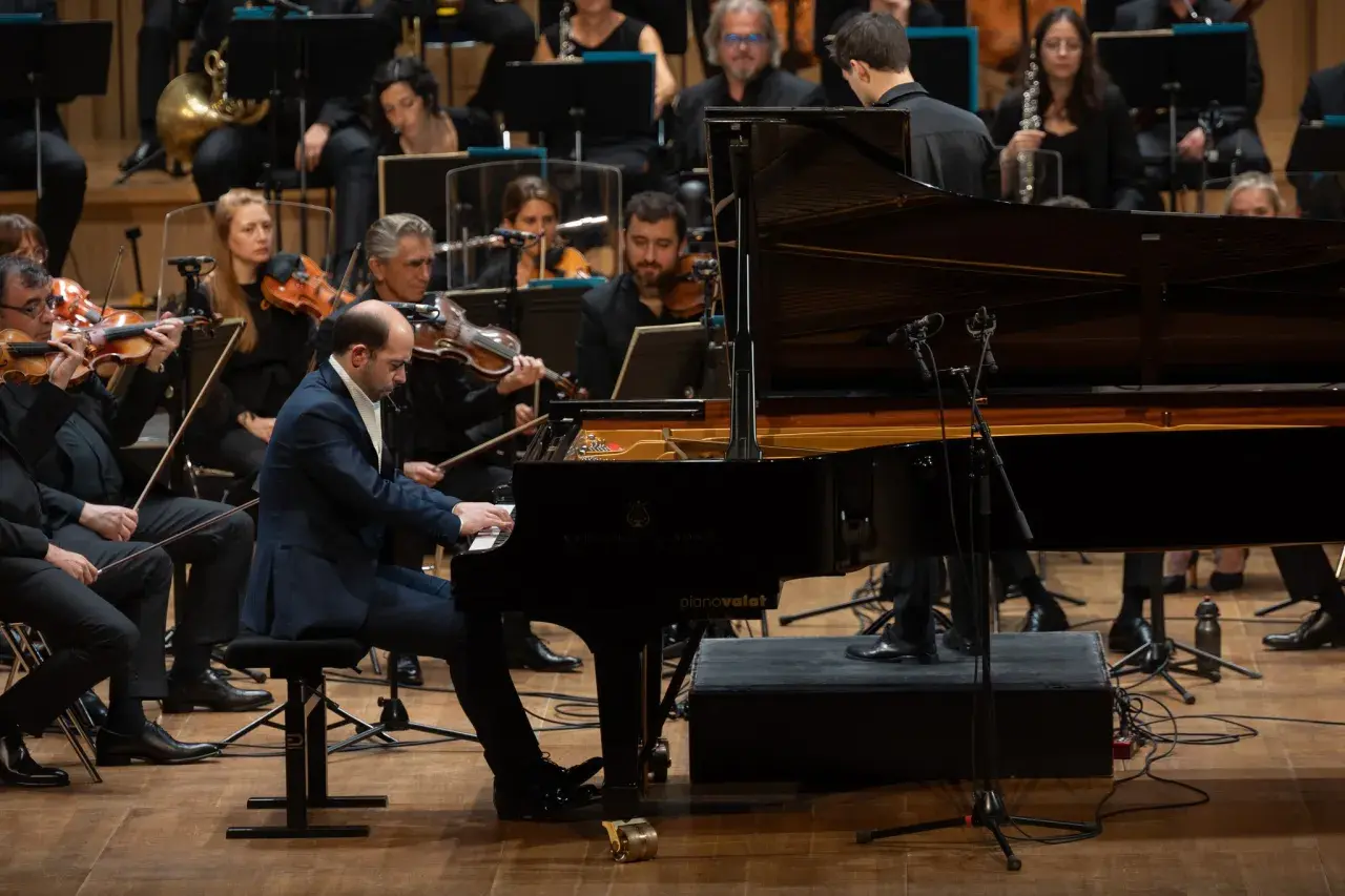 Un pianiste joue un morceau au tempo larghetto, entouré par un orchestre symphonique.