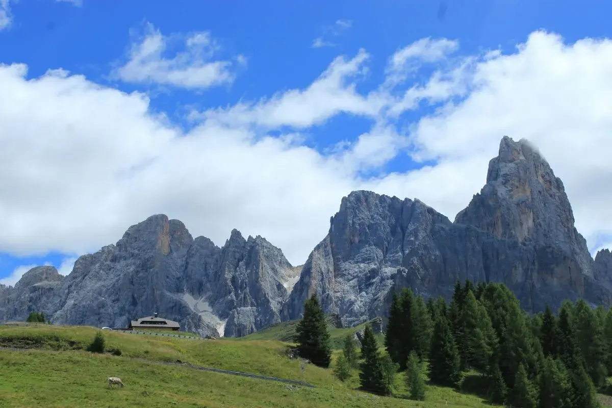 Majestuosas montañas de los Picos de Europa, un paisaje ideal para recorrer con tu camper. Nubes blancas adornan el cielo azul.
