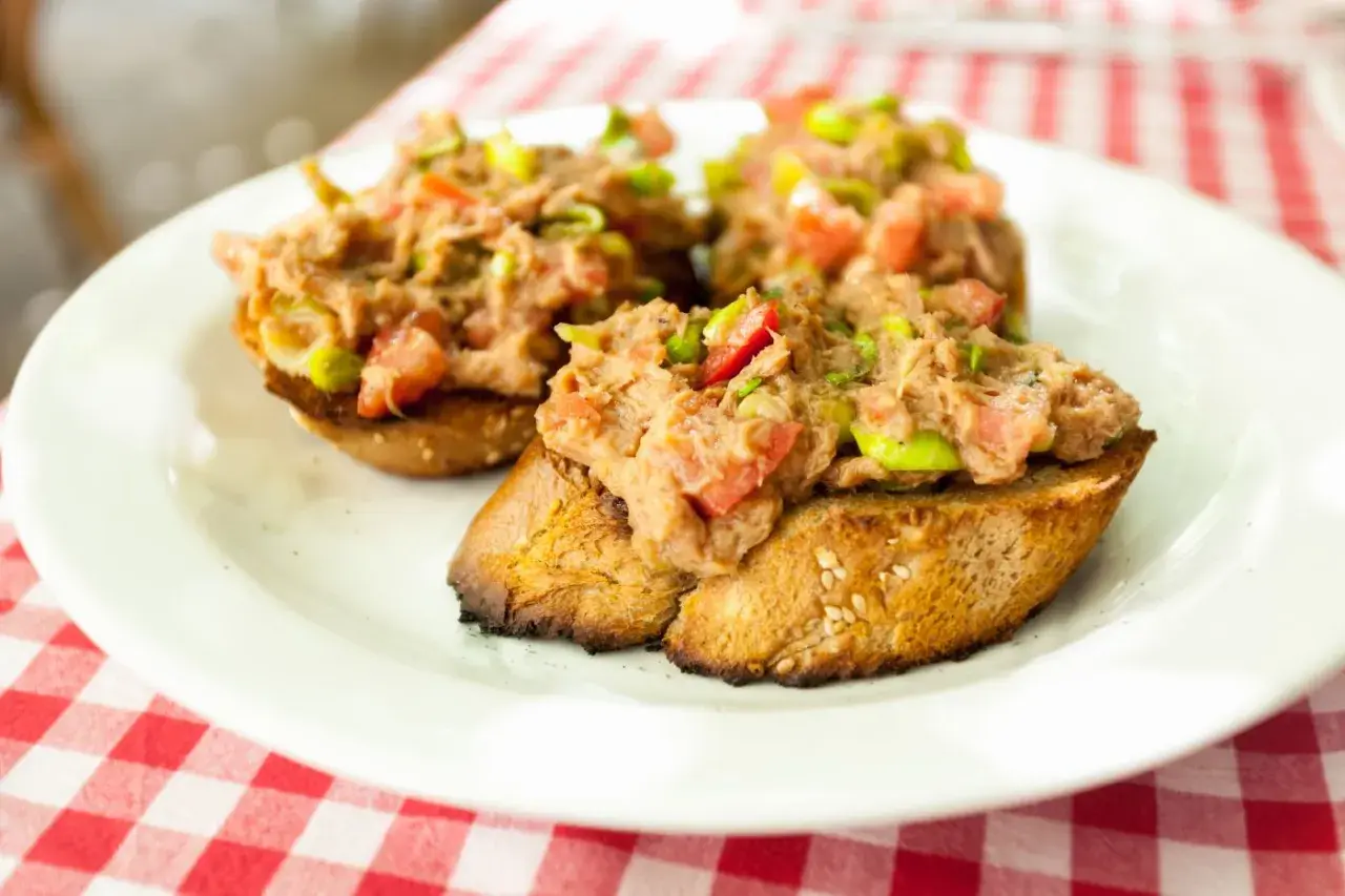 Trzy chrupiące kromki chleba z pastą z tuńczyka, pomidorów i zielonej cebulki. Idealna bruschetta z tuńczykiem na letni obiad.