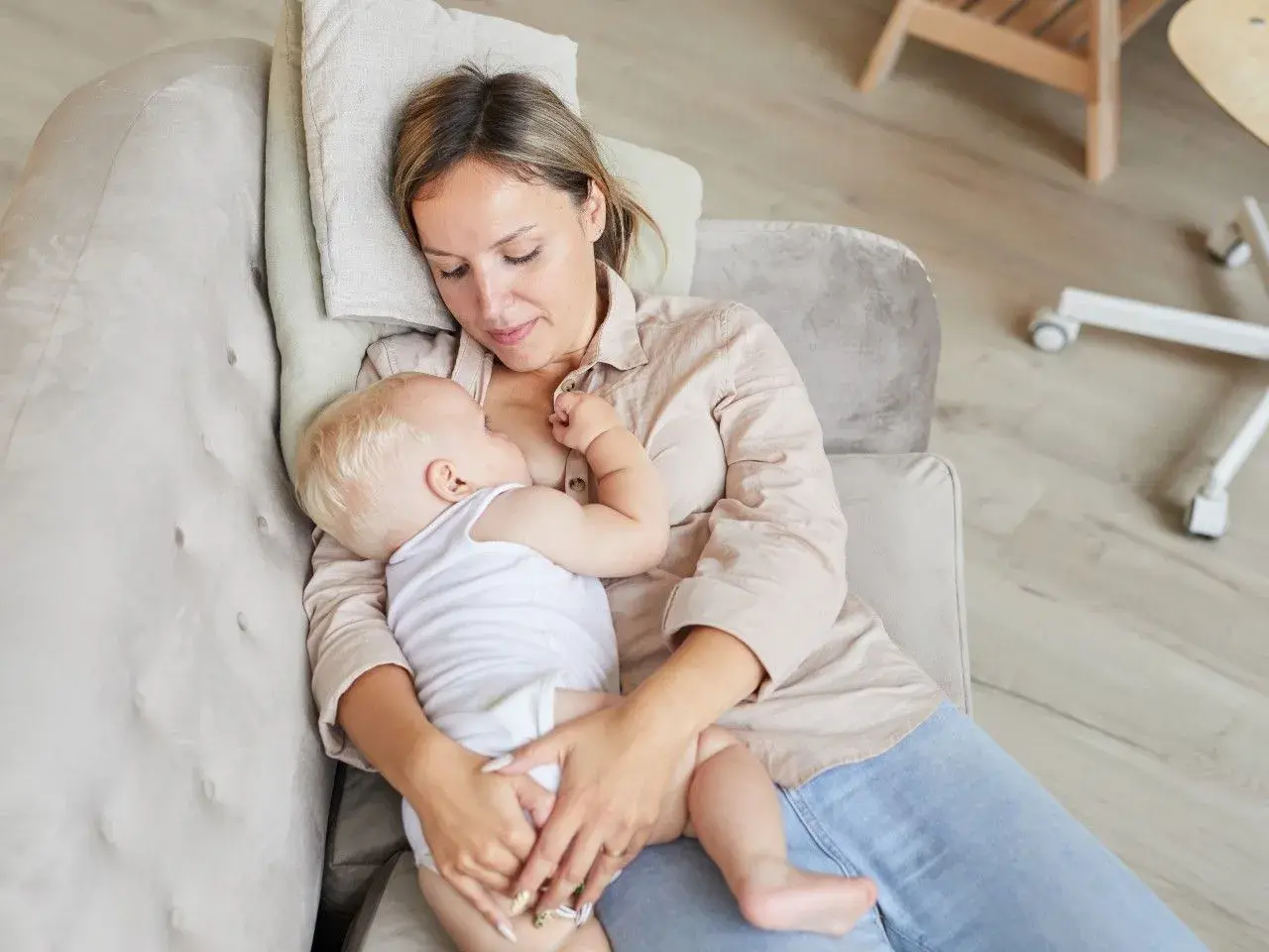 Ciepłe chwile karmienia spod pachy. Mama tuli dziecko, karmiąc je piersią na kanapie.