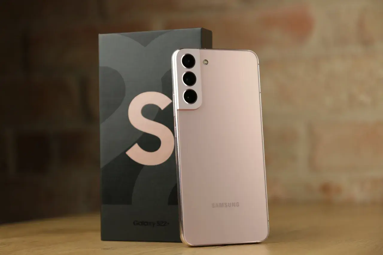 Różowy Samsung S22 Plus obok swojego czarnego pudełka z dużym logo "S".