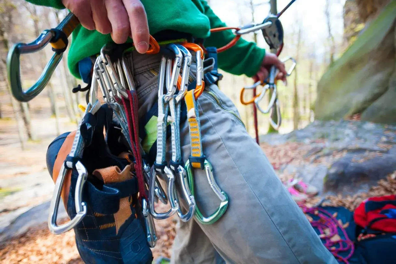 Kletterer mit Ausrüstung, darunter Kletterschuhe und Karabiner, bereit für die selbstsicherung beim Klettern.