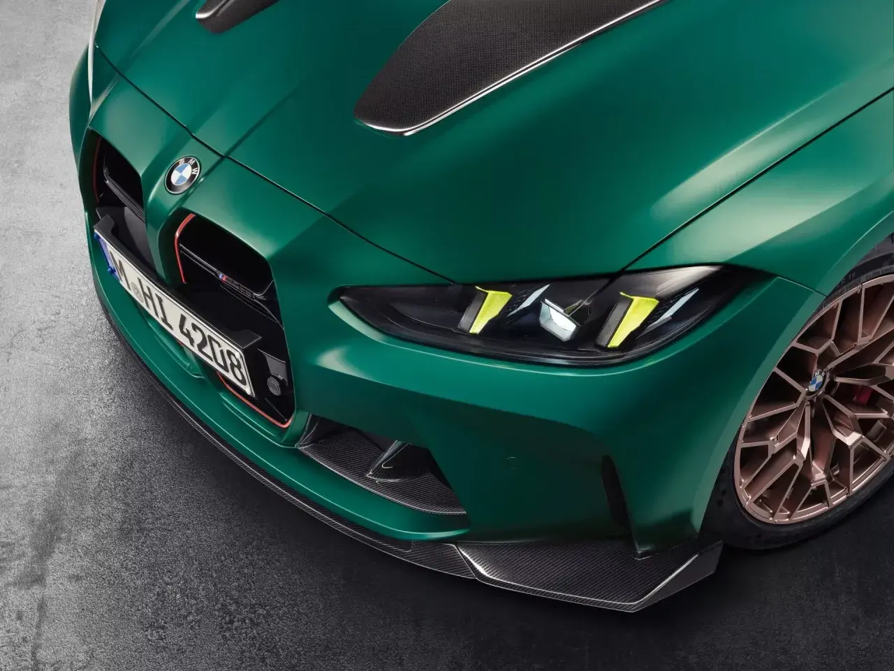 Przód zielonego BMW M4 CSL z detalami z włókna węglowego i złotymi felgami.
