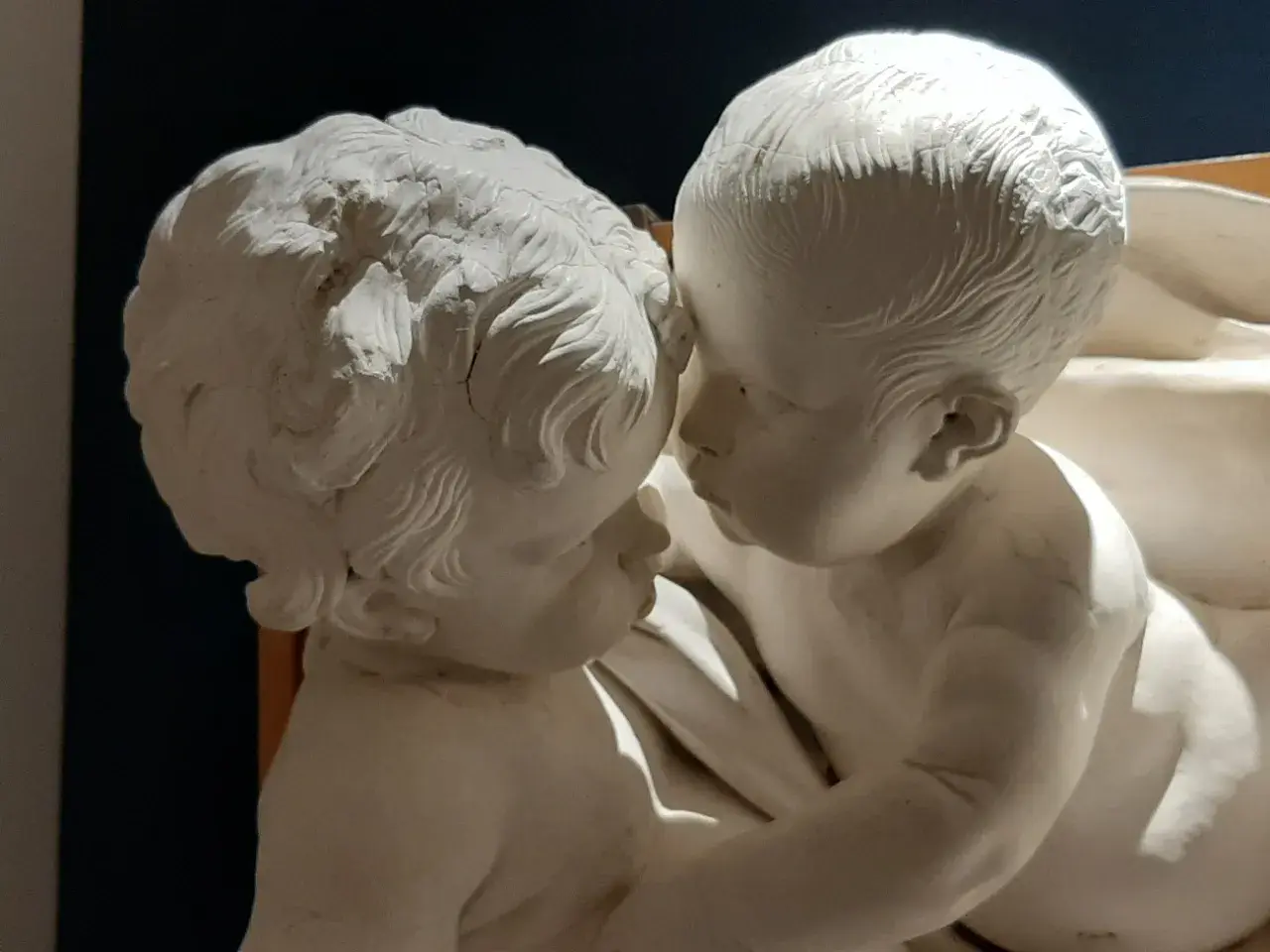 Due putti in stucco, un'opera di Giacomo Serpotta, si abbracciano teneramente.