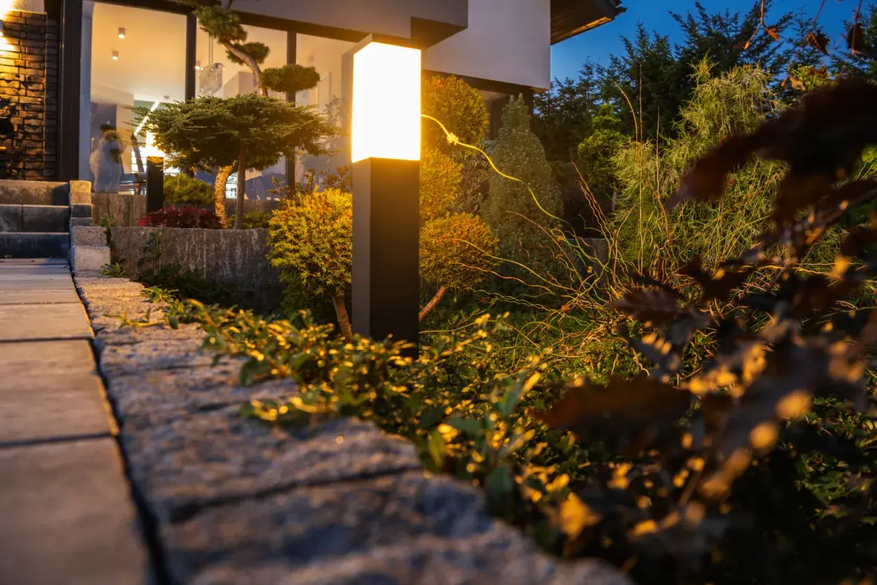 Nowoczesna lampa oświetla ogród, tworząc magiczną atmosferę. Zobacz, jak oświetlić ogród, by był piękny nocą.