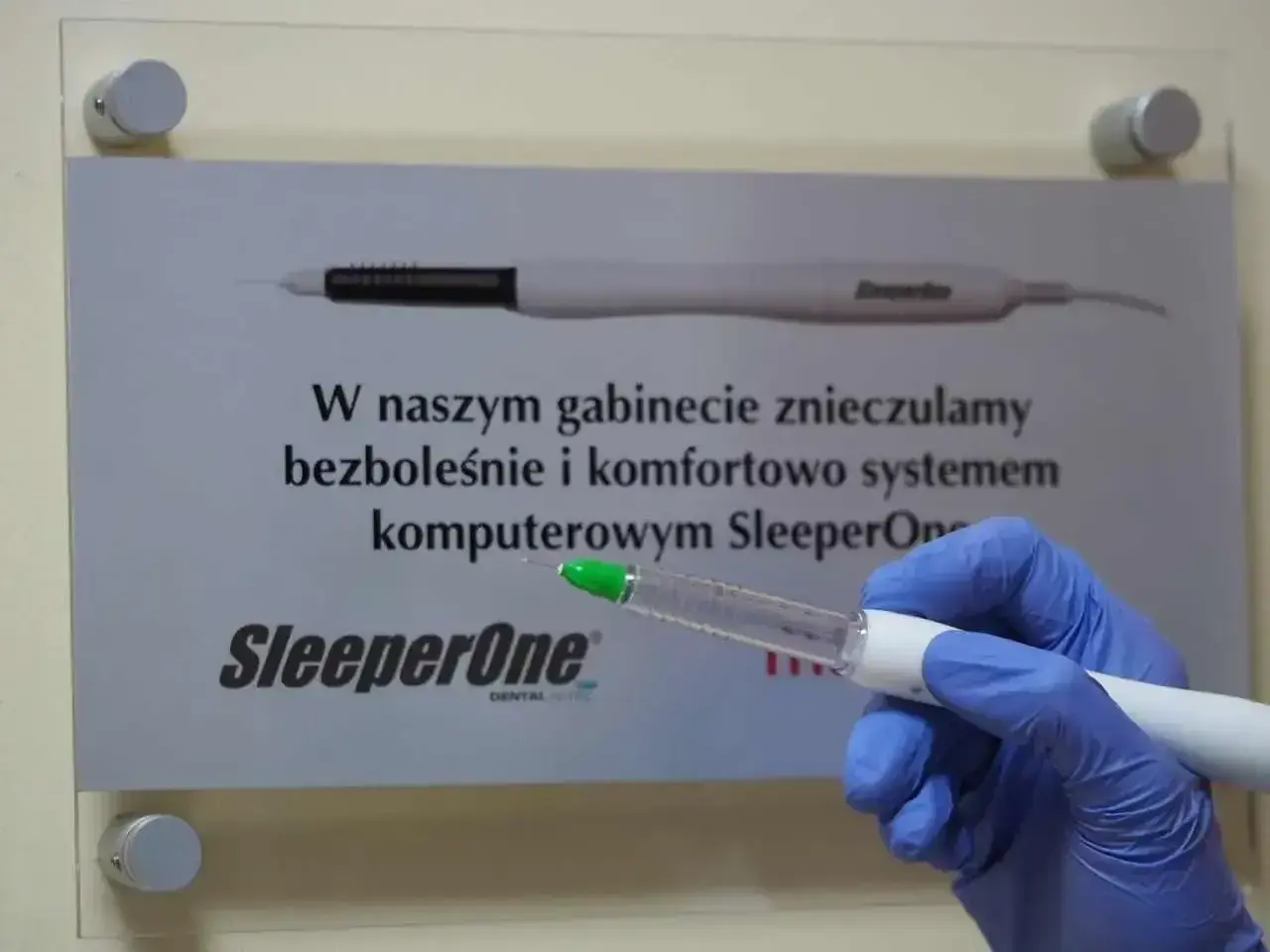 Ręka w niebieskiej rękawiczce trzyma komputerowy system znieczulający SleeperOne. Dowiedz się, ile trzyma znieczulenie u dentysty.