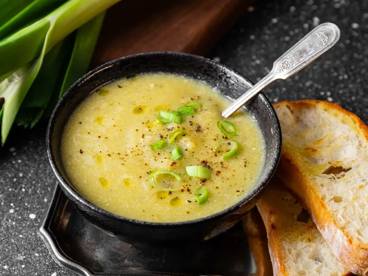 Un réconfortant velouté de poireaux pommes de terre, garni de ciboule et servi avec du pain grillé.