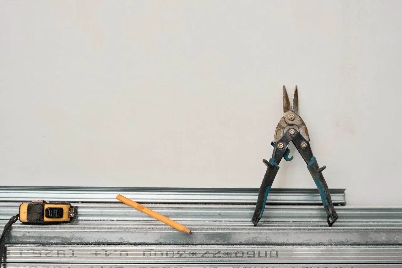 Outils pour comment couper un rail de placo : cisaille, mètre, crayon. Prêt à construire !