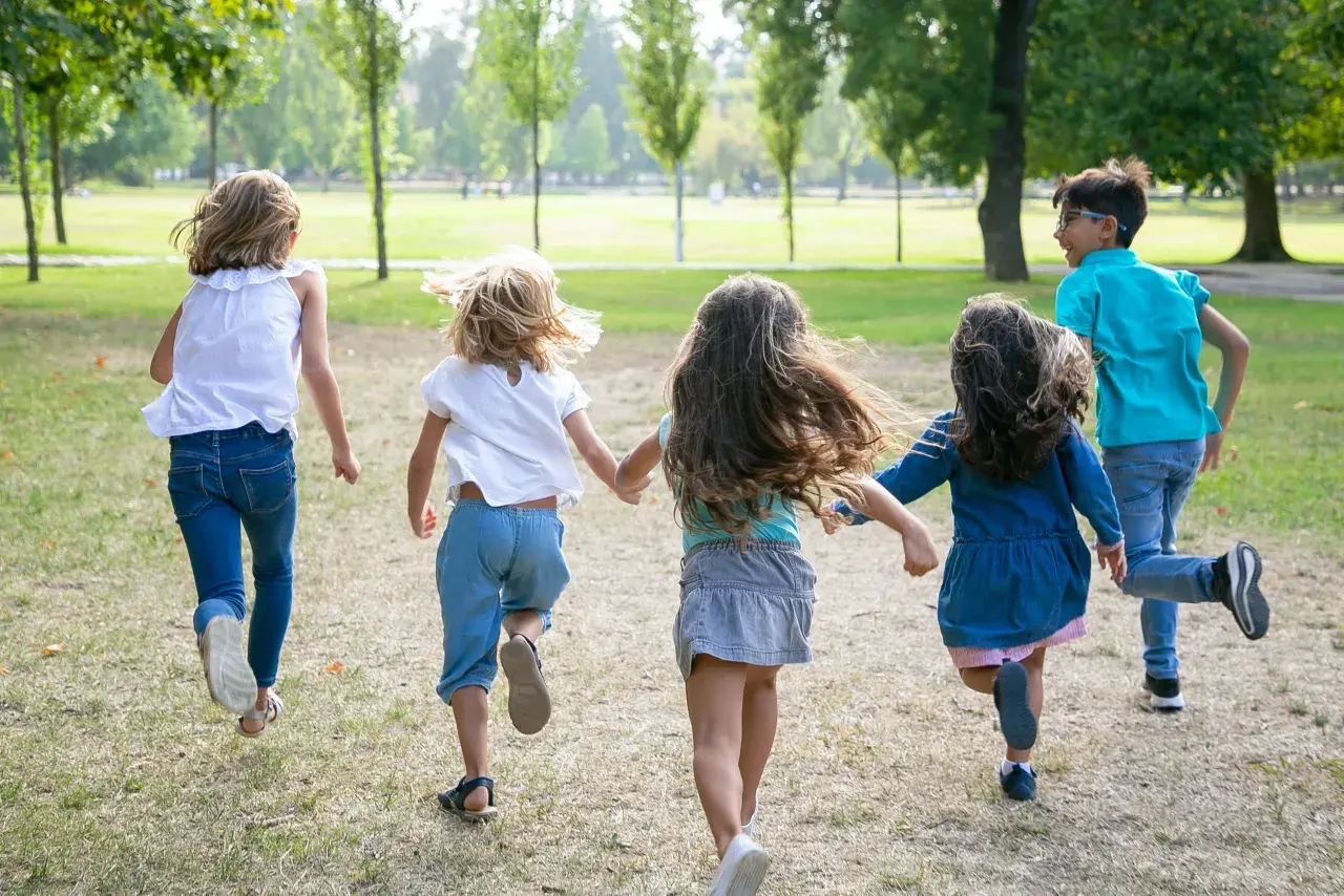 Niños corriendo en un parque, disfrutando de la **infantil primavera**.