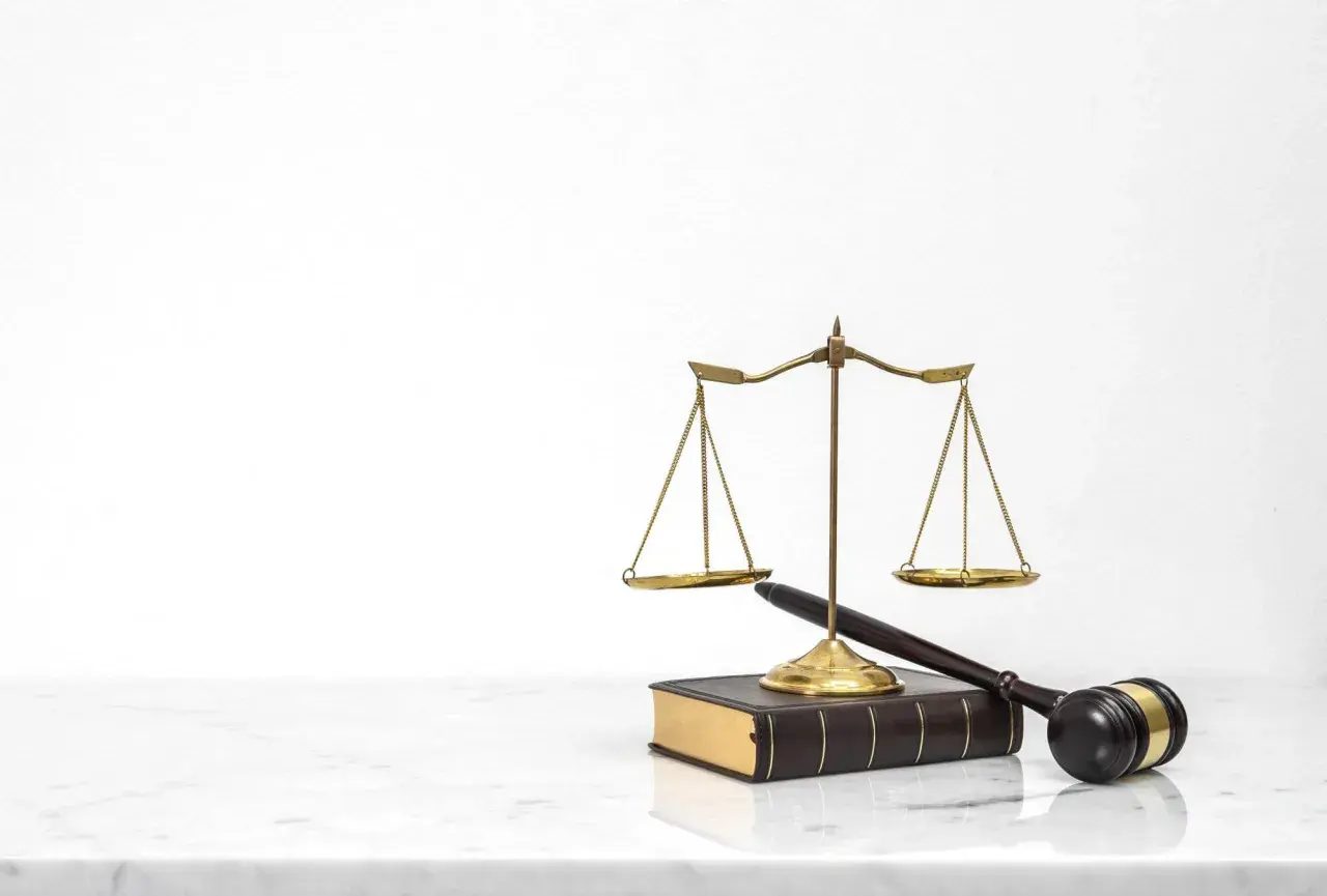Waga sprawiedliwości, młotek sędziowski i księga prawa. Symbolizują sprawiedliwy proces, który może zadecydować o tym, kto zostanie jedynym spadkobiercą testamentowym.
