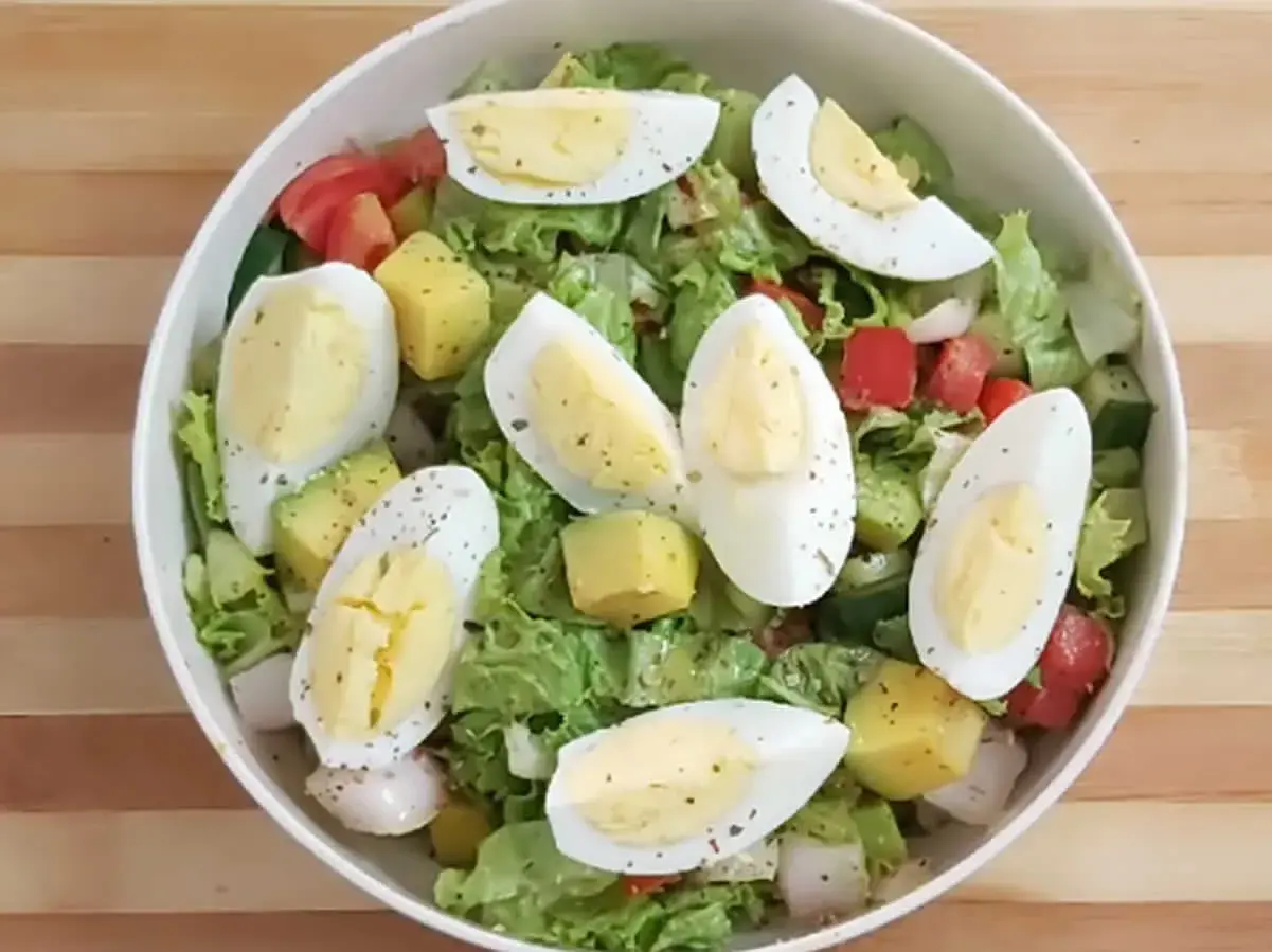 Salade colorée avec avocat, œuf dur coupé en quartiers, tomates, concombres et laitue. Un délice frais et équilibré.