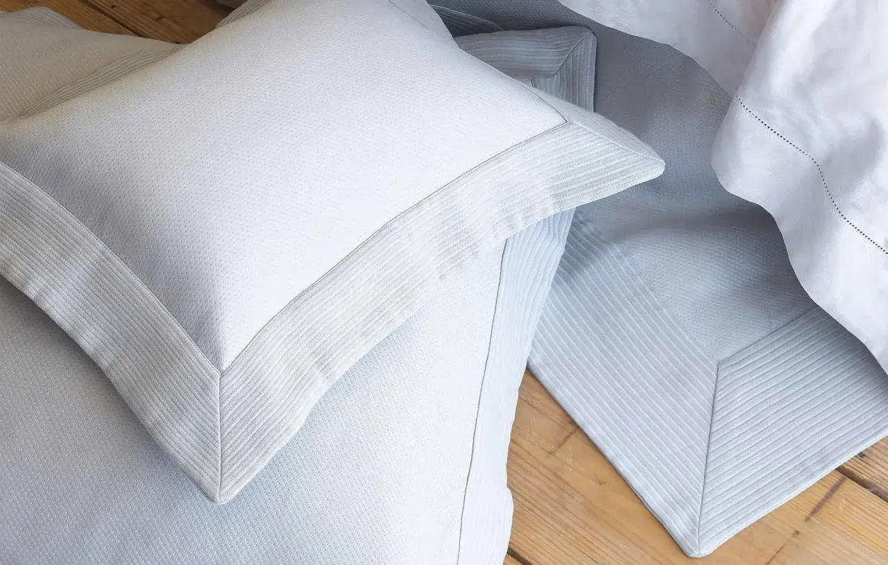 Close-up of white pillow shams with decorative borders, often used to dress up a bed and protect pillows.